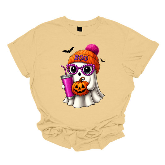 Bring on the spooky-cute vibes with this adorable fall tee! 👻🎃 The design features a sweet little ghost bundled up in an orange sock cap with a pink pom on top. The flipped brim of the hat reads “BOO” for a playful touch. This stylish ghost also sports purple reading glasses, holds a matching purple drink cup, and carries a tiny jack-o’-lantern bucket — ready for all the fall fun! Two little bats flutter in the background to complete the whimsical Halloween scene. Gorgeousware.com