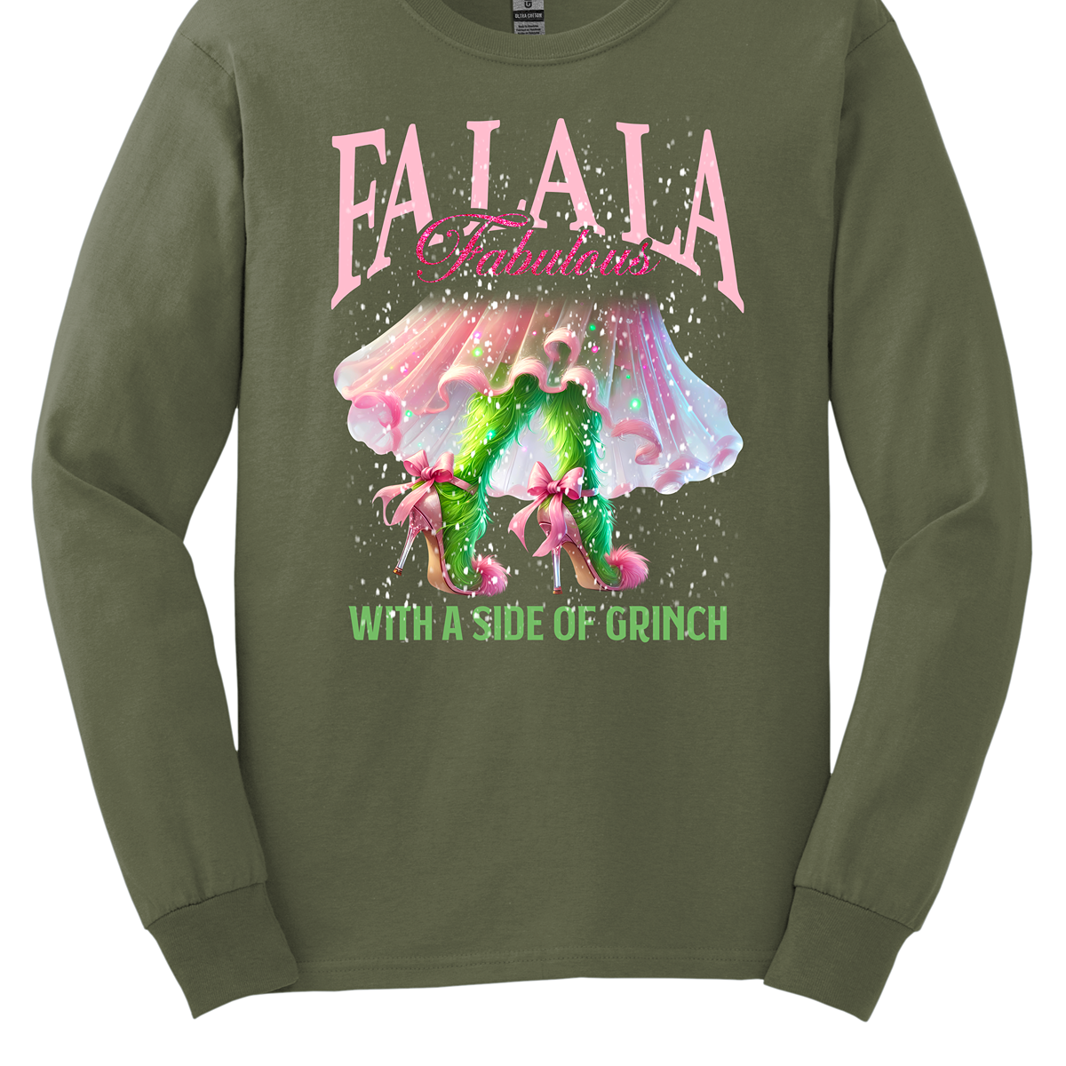 The design features a playful and festive take on the Grinch character with a stylish twist. The phrase "Fa La La Fabulous" is at the top in a fun, cursive font with a bouncy, holiday-inspired feel. The word "Fabulous" stands out in bold, glamorous lettering with subtle sparkles, giving it a chic vibe. Below, the Grinch is shown with her girly green legs, styled in light pink high heels adorned with oversized bows at the back, adding a sweet and fashionable touch. Shop at Gorgeousware.com