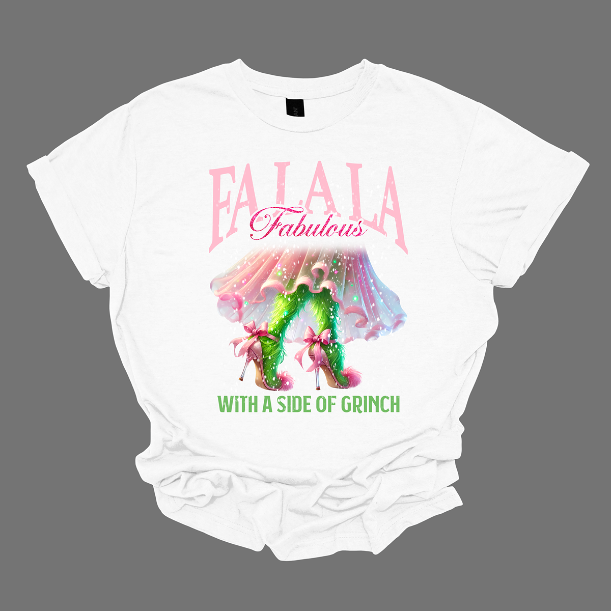 The design features a playful and festive take on the Grinch character with a stylish twist. The phrase "Fa La La Fabulous" is at the top in a fun, cursive font with a bouncy, holiday-inspired feel. The word "Fabulous" stands out in bold, glamorous lettering with subtle sparkles, giving it a chic vibe. Below, the Grinch is shown with her girly green legs, styled in light pink high heels adorned with oversized bows at the back, adding a sweet and fashionable touch. Shop at Gorgeousware.com