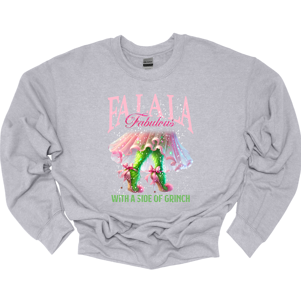 The design features a playful and festive take on the Grinch character with a stylish twist. The phrase "Fa La La Fabulous" is at the top in a fun, cursive font with a bouncy, holiday-inspired feel. The word "Fabulous" stands out in bold, glamorous lettering with subtle sparkles, giving it a chic vibe. Below, the Grinch is shown with her girly green legs, styled in light pink high heels adorned with oversized bows at the back, adding a sweet and fashionable touch. Shop at Gorgeousware.com