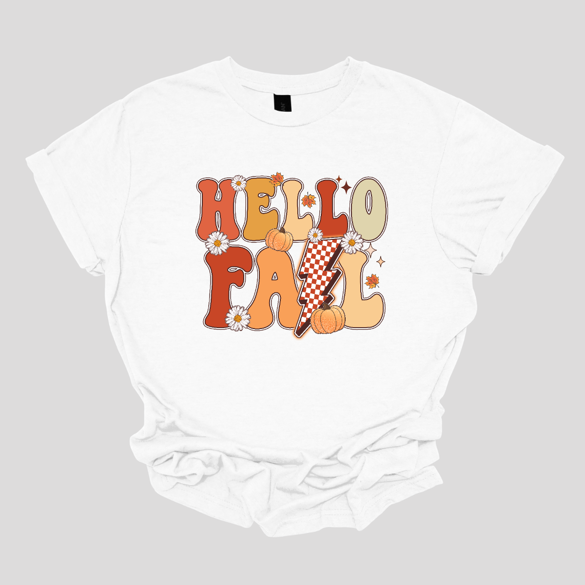 The t-shirt design features a vibrant and nostalgic retro aesthetic. At the center, the phrase "Hello Fall" is boldly displayed in a playful, vintage-inspired font. The letters are rendered in varying shades of orange and yellow, capturing the warm hues of autumn. Shop at Gorgeaousware.com