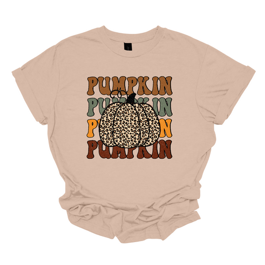 The t-shirt features the word "Pumpkin" repeated four times vertically down the center. Each instance of "Pumpkin" is rendered in a distinct fall color. The colors include rich oranges, deep reds, golden yellows, and warm browns, evoking the vibrant hues of autumn. At the top of these stacked words, there is a large, eye-catching pumpkin illustrated in bold cheetah print. The cheetah print design on the pumpkin adds a playful and trendy twist. Shop Gorgeousware.com