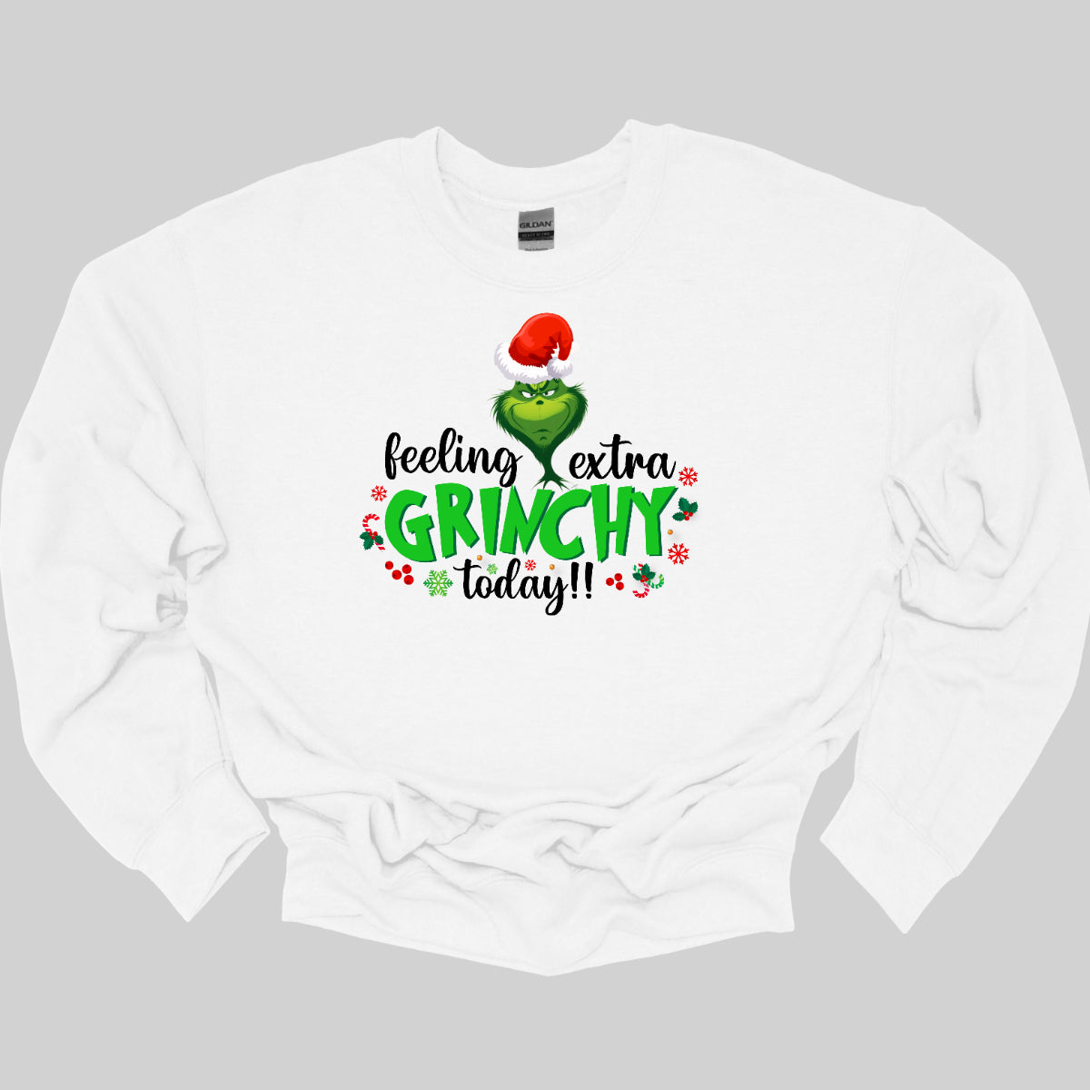 This T-shirt design exudes festive cheer and playful humor with its vibrant and eye-catching elements. The front of the shirt features the phrase, "Feeling extra grinchy today!!" prominently displayed in a fun and engaging. Shop Gorgeousware.com