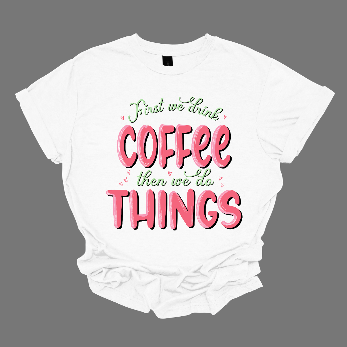 A playful and relatable garment for those who understand the importance of starting the day right. This shirt is a witty declaration that coffee is the essential first step before diving into the hustle and bustle of daily activities.  The design features a clever and eye-catching arrangement of the phrase "First We Do Coffee, Then We Do Things," playfully emphasizing the priority of enjoying a cup of coffee before tackling the tasks of the day. Shop at Gorgeousware.com