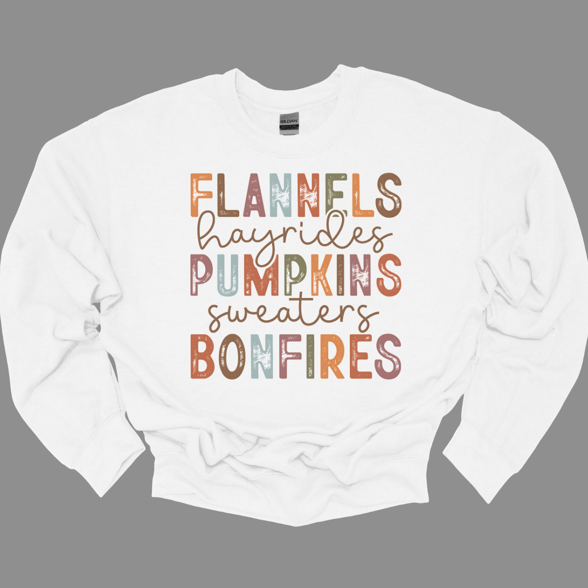 Get into the autumn spirit with our 'Fall Favorites' tee, featuring a dynamic design that celebrates all things cozy and festive! The shirt showcases the words 'Flannels,' 'Hayrides,' 'Pumpkins,' 'Sweaters,' and 'Bonfires,' each in a unique font style—from grunge print to elegant cursive. The vibrant, alternating colors add a playful touch to the design, capturing the essence of fall’s rich palette. Shop at Gorgeousware.com