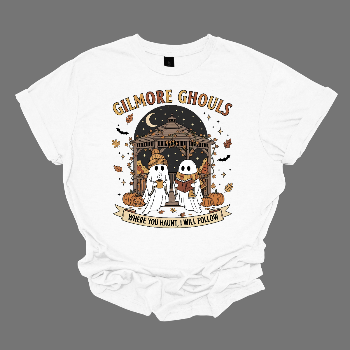 Calling all Gilmore Girls fans with a love for spooky season! 👻🍂 This Gilmore Ghouls graphic tee is the perfect mix of cozy and creepy-cute. The design features two friendly ghosts standing under a gazebo — one sipping a steaming mug, the other lost in a good book. The backdrop is filled with glowing jack-o’-lanterns, pumpkins, fluttering bats, and falling autumn leaves for the ultimate fall aesthetic. Shop at Gorgeousware.com