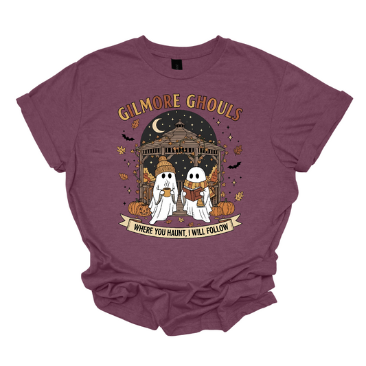 Calling all Gilmore Girls fans with a love for spooky season! 👻🍂 This Gilmore Ghouls graphic tee is the perfect mix of cozy and creepy-cute. The design features two friendly ghosts standing under a gazebo — one sipping a steaming mug, the other lost in a good book. The backdrop is filled with glowing jack-o’-lanterns, pumpkins, fluttering bats, and falling autumn leaves for the ultimate fall aesthetic. Shop at Gorgeousware.com