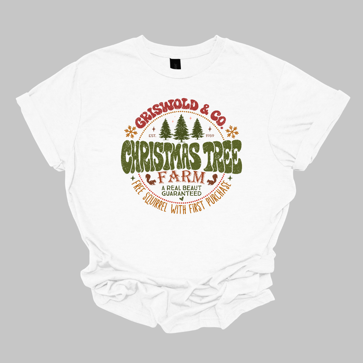 This festive t-shirt captures the spirit of holiday fun with a design inspired by classic Christmas cheer. The shirt features the words “Christmas Tree Farm” prominently displayed, with “Christmas Tree” in vibrant green bubble letters that pop with playful energy.Encircling this central text is “Griswold &amp; CO.,” giving it a nostalgic nod to the iconic family from holiday movie lore. Surrounding the main text are memorable quotes from the movie. Shop Gorgeousware.com