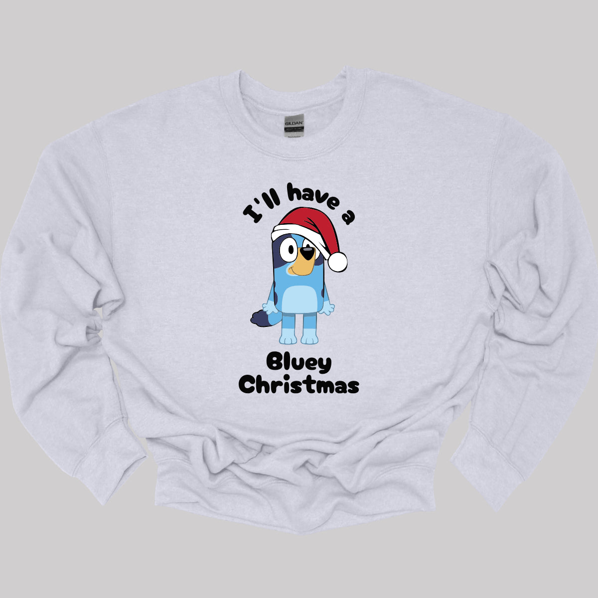 This playful t-shirt features the cheerful phrase "I'LL HAVE A BLUEY CHRISTMAS" in a fun black bubble font that adds a whimsical touch. At the center of the design, an adorable illustration of Bluey is depicted wearing a classic red and white Santa hat, perfectly capturing the festive spirit. Shop Gorgeousware.com