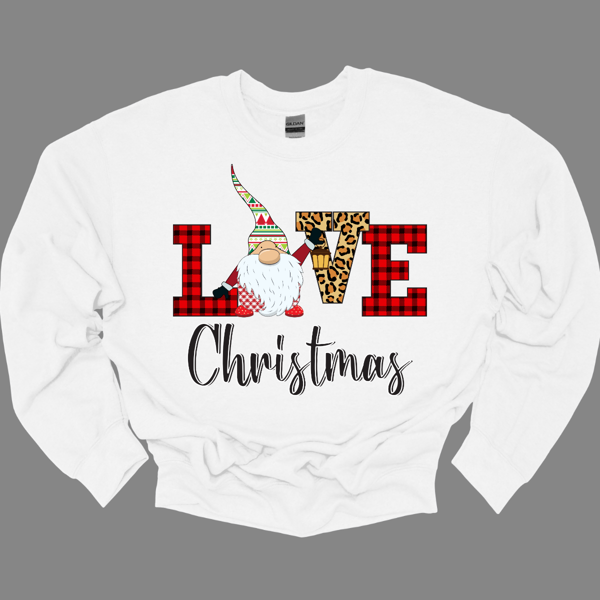 This charming t-shirt showcases the word "LOVE" in a festive and fun design. The letters "L" and "E" are styled in a classic red buffalo plaid, adding a cozy, rustic touch. The "V" pops with a bold cheetah print, bringing an unexpected and trendy flair to the design. The "O" is replaced by an adorable gnome, whose whimsical hat features a cheerful ugly sweater Christmas pattern in vibrant red, green, and white. Shop at Gorgeousware.com