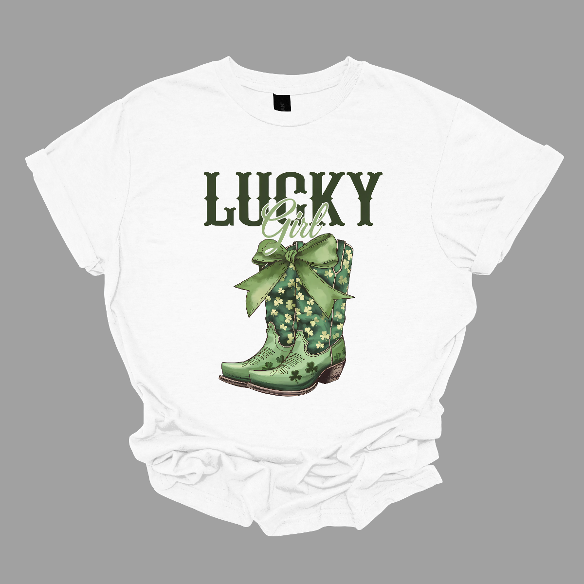 This St. Patrick's Day t-shirt features the word "Lucky" in big, bold military green letters, inspired by the iconic Lucky brand style. Below, the word "girl" is elegantly written in a lighter green, beautiful font, adding a soft touch. Beneath it, a pair of cowgirl boots with a large green bow at the top make a statement. Celebrate in style this St. Patrick's Day with this charming design, available at Gorgeousware.com