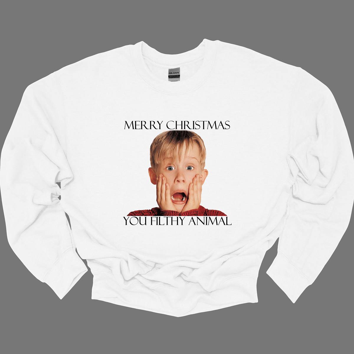 This fun and festive apparel features the iconic phrase "Merry Christmas You Filthy Animal" in bold, playful lettering, a memorable line from the Home Alone movie. The design also showcases the infamous face of Kevin McCallister, played by Macaulay Culkin, with his hands on his cheeks in a dramatic, surprised expression. Perfect for any Home Alone fan, this shirt or sweatshirt is ideal for spreading some holiday cheer and nostalgia.  Shop at Gorgeousware.com