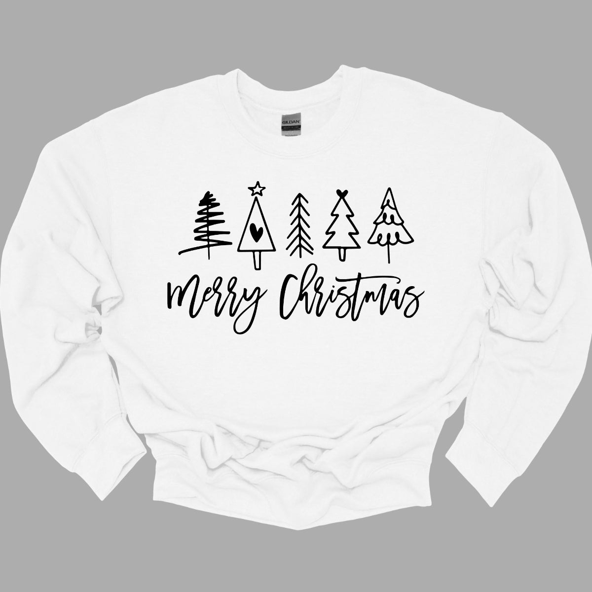 This charming t-shirt features the festive greeting "Merry Christmas" in a stylish black cursive font that flows beautifully across the front. Above the phrase, five delightful stick figure Christmas trees stand tall, each uniquely decorated to showcase its own personality. Shop Gorgeousware.com