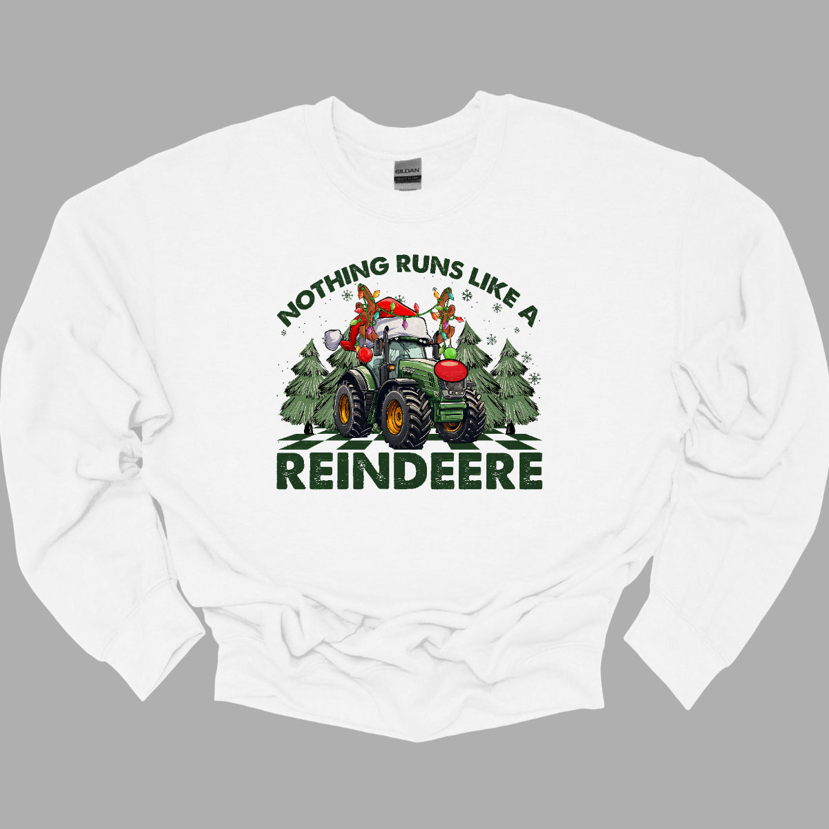 This playful t-shirt features the catchy phrase "Nothing runs like a reindeer" in bold black font, making a fun statement that’s perfect for the holiday season. At the center of the shirt, a charming John Deere tractor is decked out for Christmas: it sports a bright red nose, festive antlers, and a classic Santa hat, creating a delightful and humorous twist.&nbsp;The tractor is surrounded by whimsical Christmas trees, adding a cheerful backdrop that enhances the festive vibe. Shop Gorgeousware.com