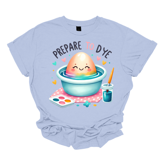 Get ready to add a splash of color to your Easter celebrations with our 'Prepare to Dye' T-shirt! This playful design features an Easter egg sitting in a bowl of dye alongside a paintbrush, capturing the excitement of decorating eggs for the holiday. Shop at Gorgeousware.com