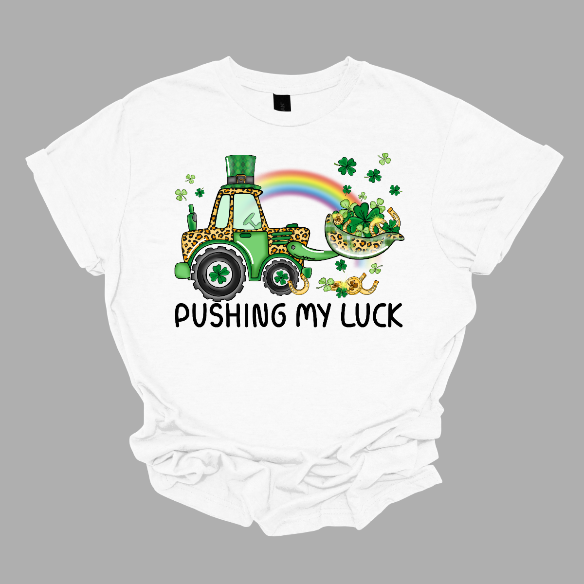 A playful and whimsical garment that captures the spirit of the holiday with a touch of fun. This shirt features a lively design with a tractor playfully shoveling a load of shamrocks, creating a unique and charming representation of pushing one's luck in a St. Patrick's Day context. The design showcases a tractor adorned with shamrocks, symbolizing the act of "pushing" luck in a light-hearted and festive manner. Shop at Gorgeousware.com