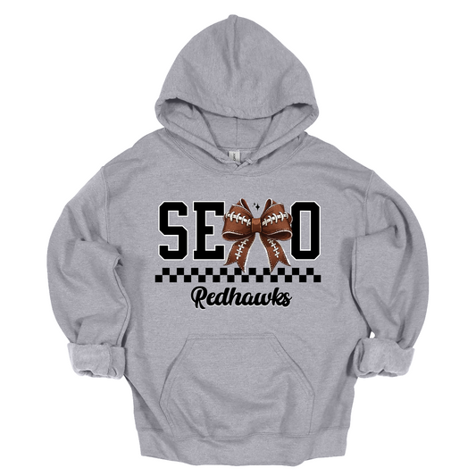 Gear up your Redhawk fan with our stylish youth SEMO apparel, available in short/ long sleeve, crewneck, and hoodie options! Featuring bold black SEMO lettering with a creative twist—the letter M is playfully replaced by a croquette football bow, adding a fun, sporty vibe. A sleek checkerboard underline ties the look together, while "Redhawks" is written in a stylish cursive script for the perfect finishing touch.
Shop at Gorgeousware.com today!
