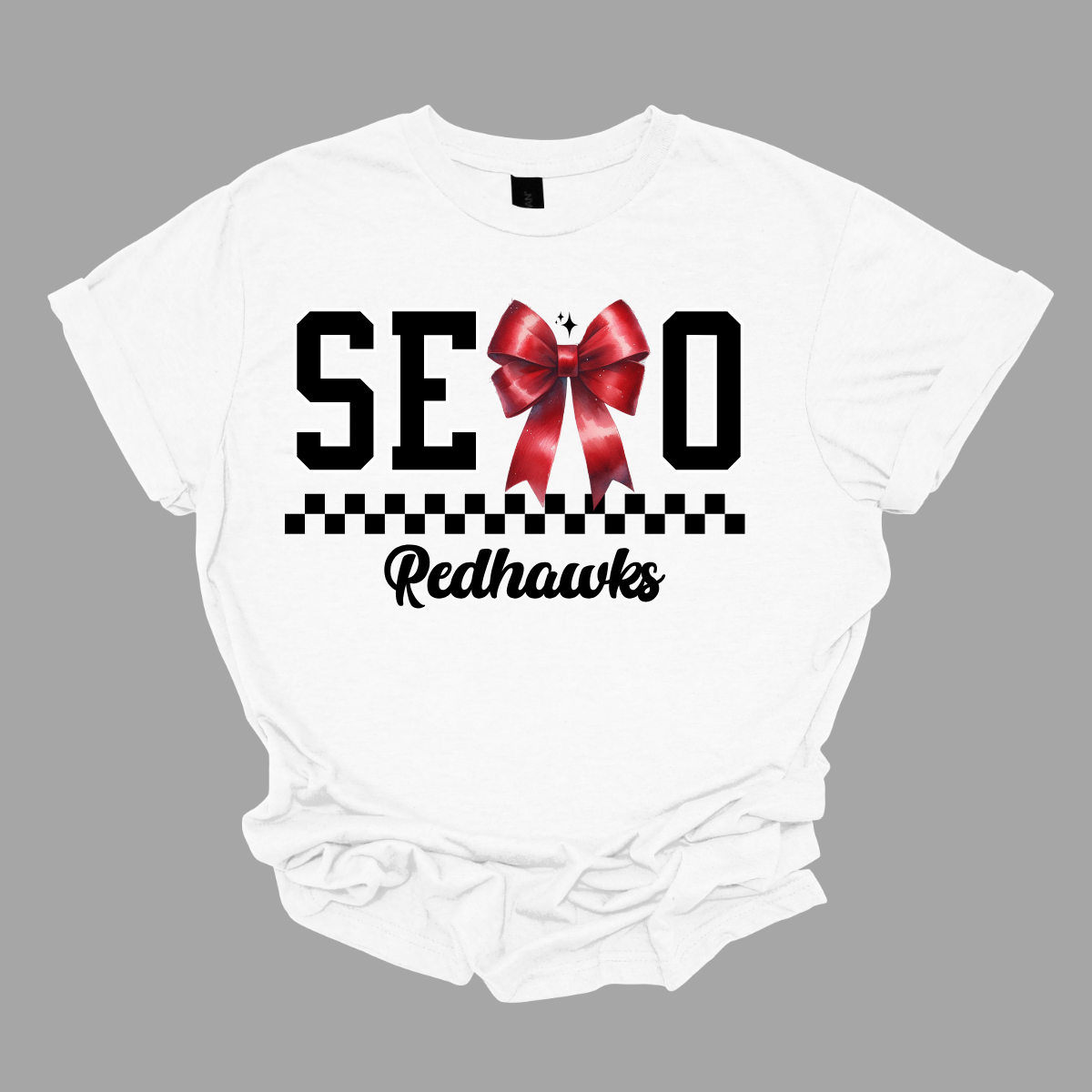 Show off your SEMO pride in style with this trendy short/long sleeve t-shirt! Featuring the bold letters "SEMO," where the "M" is cleverly replaced by a stylish red croquette bow, this shirt adds a unique twist to your wardrobe. Underneath, a playful checkerboard stripe adds a fun touch, while "Redhawks" is elegantly written in a cute cursive font, bringing a touch of flair.  Get ready to turn heads and express your school spirit! Shop at Gorgeousware.com