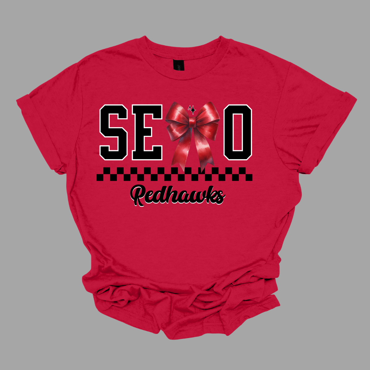 Show off your SEMO pride in style with this trendy short/long sleeve t-shirt! Featuring the bold letters "SEMO," where the "M" is cleverly replaced by a stylish red croquette bow, this shirt adds a unique twist to your wardrobe. Underneath, a playful checkerboard stripe adds a fun touch, while "Redhawks" is elegantly written in a cute cursive font, bringing a touch of flair.  Get ready to turn heads and express your school spirit! Shop at Gorgeousware.com