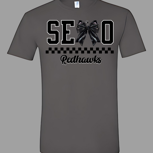 Show off your SEMO pride in style with this trendy short sleeve t-shirt! Featuring the bold letters "SEMO," where the "M" is cleverly replaced by a stylish black croquette bow, this shirt adds a unique twist to your wardrobe. Underneath, a playful checkerboard stripe adds a fun touch, while "Redhawks" is elegantly written in a cute cursive font, bringing a touch of flair. Shop at Gorgeousware.com