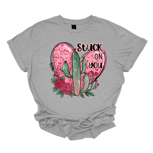 Introducing our "Stuck On You" T-shirt – a playful and charming garment that beautifully blends romance with a touch of desert whimsy. This shirt features an endearing heart entwined with a cactus, creating a delightful design that captures the essence of love with a hint of humor. Shop at Gorgeousware.com