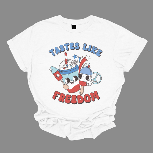 The design titled "Tastes Like Freedom" captures the essence of American patriotism and fun summer vibes. The phrase "Tastes Like Freedom" is displayed in bold, playful lettering with a red, white, and blue color scheme, evoking the colors of the American flag. 
In the picture, a Bomb Pop, a peace sign, firework, and cool drink symbolizing childhood memories and summer enjoyment. Shop Gorgeousware.com