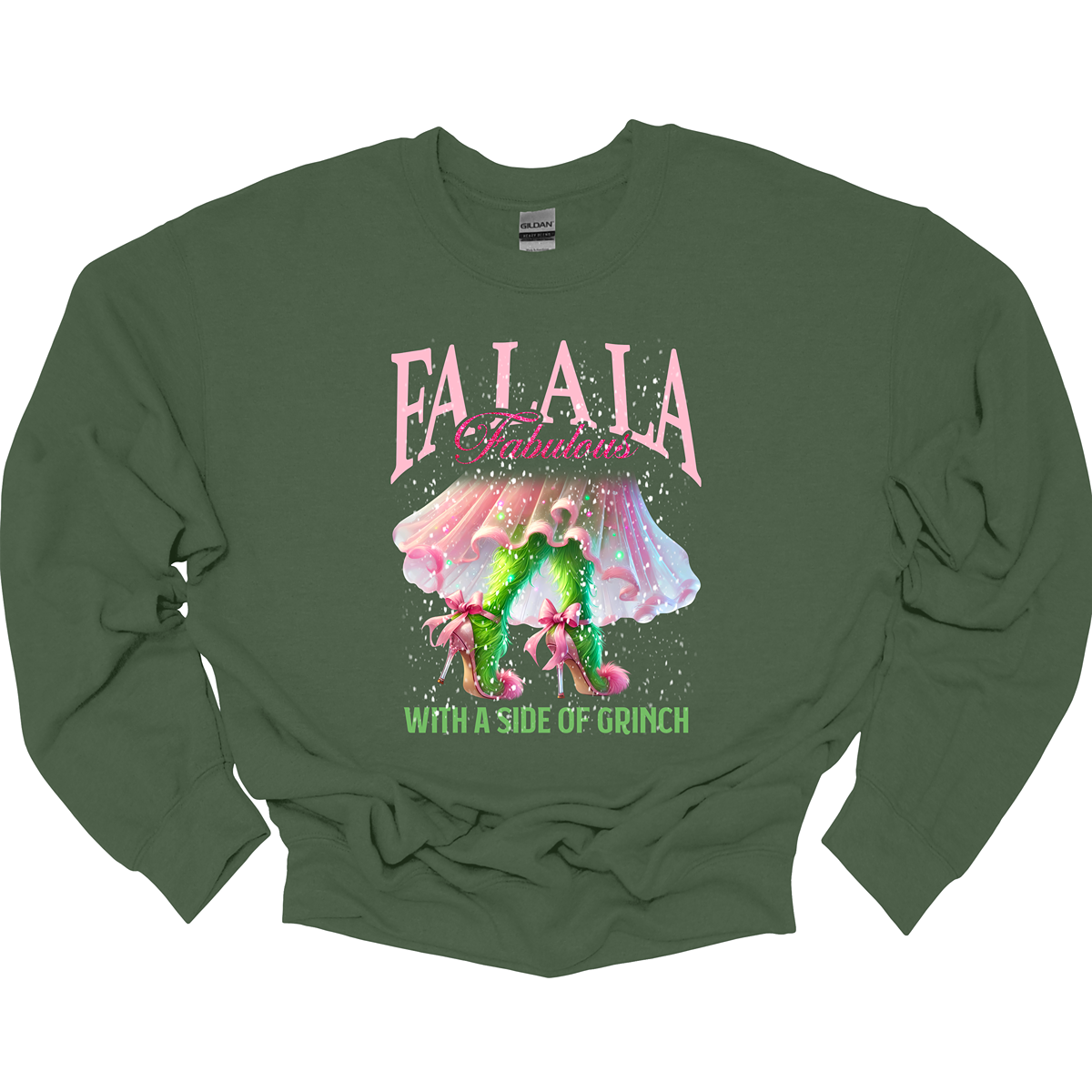 The design features a playful and festive take on the Grinch character with a stylish twist. The phrase "Fa La La Fabulous" is at the top in a fun, cursive font with a bouncy, holiday-inspired feel. The word "Fabulous" stands out in bold, glamorous lettering with subtle sparkles, giving it a chic vibe. Below, the Grinch is shown with her girly green legs, styled in light pink high heels adorned with oversized bows at the back, adding a sweet and fashionable touch. Shop at Gorgeousware.com