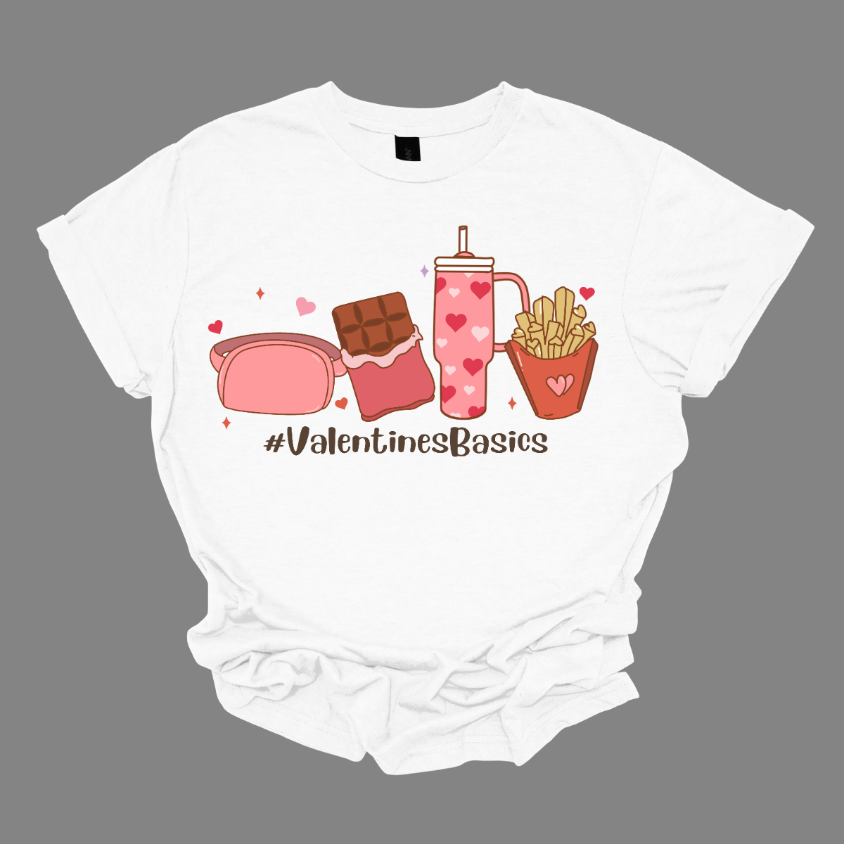 Introducing our "#ValentineBasics" T-shirt – a stylish and playful ensemble that captures the essence of Valentine's Day with a touch of everyday essentials. This shirt is a trendy celebration of the things that make this romantic holiday uniquely delightful. The design features the hashtag "#ValentineBasics" displayed prominently, complemented by illustrations of a Lululemon shoulder bag, a box of chocolates, the iconic Stanley Cup, and a side of fries. Shop at Gorgeousware.com