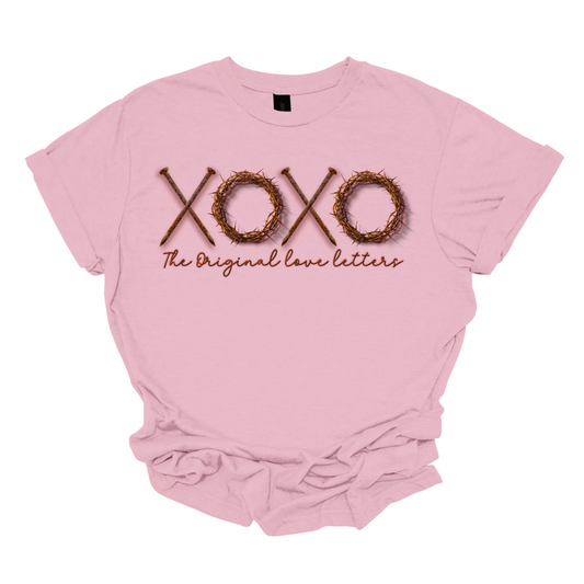 Experience the profound fusion of faith and love with our 'XOXO: The Original Love Letters' Religious T-shirt. This unique design redefines the classic X's and O's, incorporating rustic nails and a crown of thorns to symbolize the sacrificial love and redemption found in religious teachings. The shirt beautifully marries style with spiritual depth, offering a powerful expression of love grounded in faith.